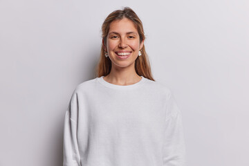 Portrait of cheerful long haired woman smiles toothily being in good mood dressed in casual sweatshirt has piercing in nose isolated over white background. People postive emotions and feelings concept - 639694239
