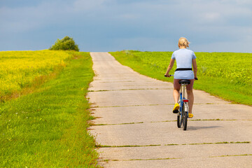 Fototapeta premium Ryazan, Russia - July 18, 2023: girl riding a bike on a country road.