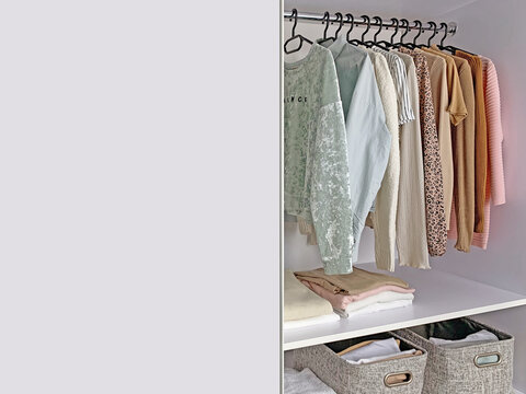 Women's wardrobe sweatshirts, shirts and blouses in neutral light colors. Concept: organization of the perfect order in the wardrobe or closet.
White wardrobe with stylish clothes and copy space