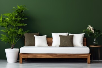 Cozy wooden sofa with white cushions near dark green wall. Side table with houseplant and potted tree. Scandinavian interior design