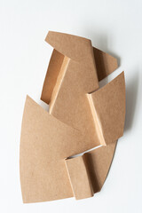 abstract brown cardboard shape with folded elements and sharp almost serrated edges on white