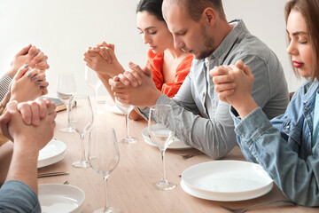 Group of people praying before dinner at table