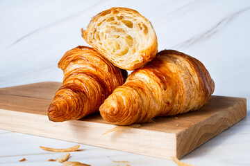 Croissant on wooden table over white marble background closeup