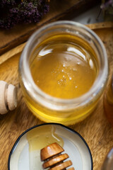 fresh natural  linden honey in glass jar with wooden  honey spoons around herb flowers