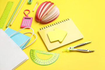 Composition with paper bag and different stationery on yellow background, closeup