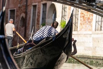 Fototapeta na wymiar Venetian gondola with gondoliere, under the bridge.
