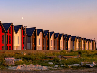 Rows of newly built colorful townhouses for sale in suburbia at summer sunset