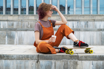Skateboarding summer sporty urban leisure activity. Skateboarder young woman resting drinking...