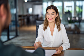 Smiling mature business woman hr handshaking hiring recruit at job interview. Happy mid aged professional bank manager, insurance agent, lawyer making contract deal with client at work office meeting.