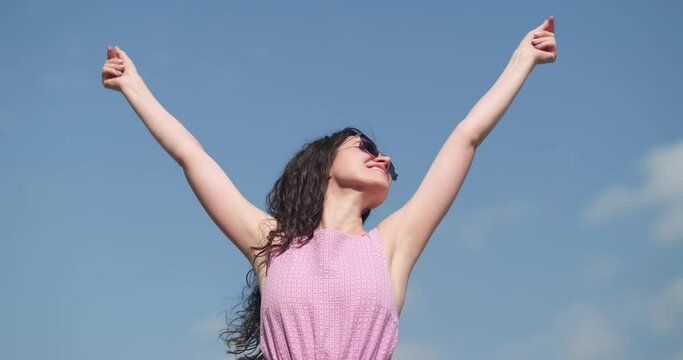 Happy relaxed woman breathing fresh air raising arms over blue sky at summer, Dreaming, freedom and traveling concept.