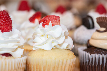 Vanilla cupcakes with vanilla frosting and strawberry toppings on dessert table