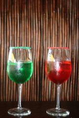 Ricos cócteles en un vaso con frutos rojos y verdes con rodaja de limón sobre un fondo de madera,...