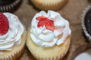 Vanilla cupcakes with vanilla frosting and strawberry toppings on dessert table