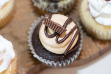 Chocolate cup cakes with whip cream and chocolate candy toppings on dessert table wedding reception