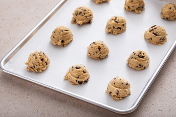 Chocolate chip cookie dough scoopes on a cookie sheet ready to be baked - Powered by Adobe