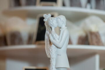 Bride and groom passionately kissing ceramic cake toppers on top of cake and infromt of out of focus cup cakes mid