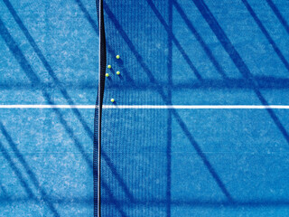 aerial zenithal image of five balls on a blue artificial grass paddle tennis court