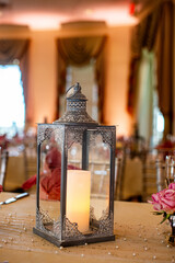 Black ornate candle lantern centerpiece on wood table at Wedding reception