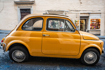 Side view of Small yellow classic Italian car on Rome, Italy, street 