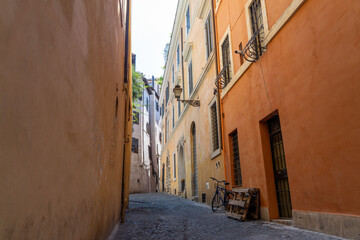 Fototapeta na wymiar Bike leans against terracotta wall on Roman street in the Ponte area of Rome, Italy on summers day - Landscape 