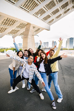 Happy young group of teenager friends having fun together outdoors. Millennial diverse friends screaming while taking photo together, enjoying free time in city street. Friendship and youth community