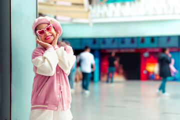 Retrato de linda niña sonriente con los brazos levantados y estilo unico con atuendo rosa y gafas...