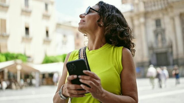 Middle age hispanic woman tourist woman using smartphone at the street