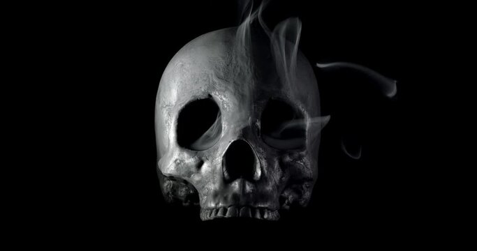 Smoke slowly creeping through the eye sockets of a terrifying human skull, haunted spirt, or frightening ghost for Halloween or other spooky scene.