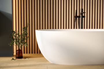 Stylish white bathtub on parquet floor with back faucet in bright bathroom, blue and wooden wall...