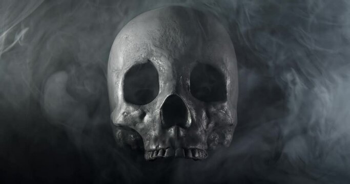 Smoke slowly clearing around a terrifying human skull, haunted spirt, or frightening ghost for Halloween or other spooky scene.