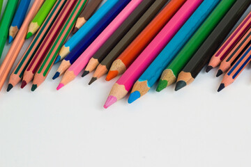 Jumbo size,colorful dry paint pencils on the white surface with copy space