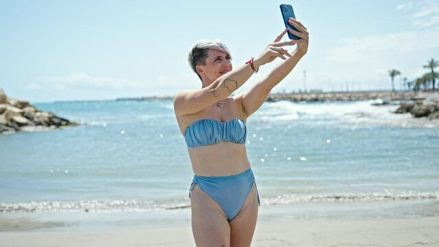 Young woman tourist wearing bikini make selfie by smartphone at beach