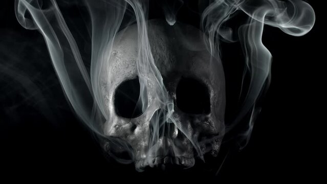 Smoke slowly creeping around a terrifying human skull, haunted spirt, or frightening ghost for Halloween or other spooky scene.