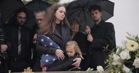 Funeral, family and sad people with American flag, grief and mourning death, burial and widow depressed at farewell event. Kid, mother and group gathering at coffin, casket and crying at ceremony