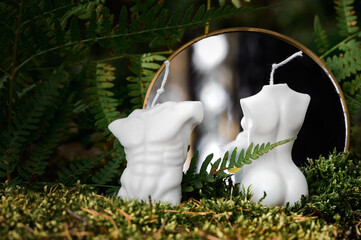 Białe eko świeczki z naturalnych składników w kształcie kobiety i mężczyzny w lecie na mchu w paprociach, odbicie w lustrze