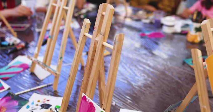 Process of drawing, group class of talented students with painting easels and canvases during lesson of watercolour painting outdoors, drawing class for adult artists in art school 