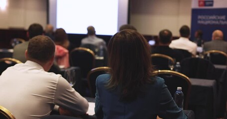 Audience at the conference hall listens to lecturer, people on a congress together listen to speaker on a stage at master-class, college students in the auditorium, corporate business seminar

