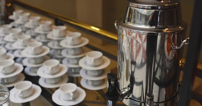 Set of coffee break lunch in the hotel restaurant during conference meeting, with tea and coffee catering, decorated banquet table with white tableware and metal tea maker machine boiler
