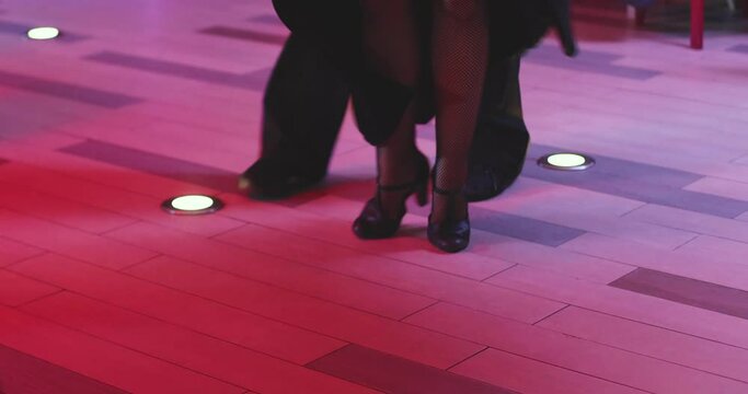 Couples dancing traditional latin argentinian dance milonga in the ballroom, tango salsa bachata kizomba lesson in the red and purple lights, festival, lesson class in dance school class academy
