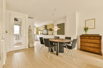 a dining room with white walls and wood flooring in the center of the room is an open kitchen area