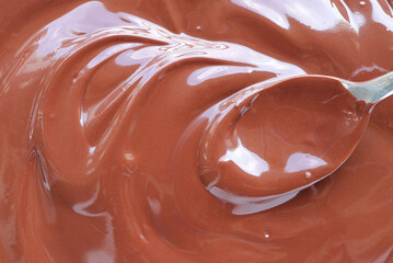 Close up of Hand stirring melted chocolate with spoon. Chocolate surface, melted premium chocolate...