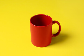 One red ceramic mug on yellow background