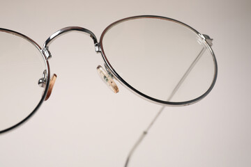 Stylish pair of glasses with metal frame on beige background, closeup
