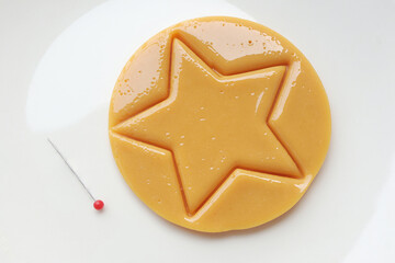 Dalgona candy or Ppopgi. Sugar Honeycomb cookie with star shape and needle on white plate. candy challenge