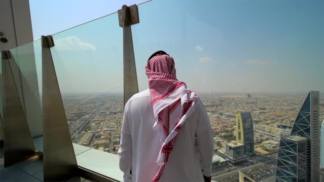 Arabic man with headscarf walking in a terrace viewpoint to watch the city of Riyadh in Saudi Arabia
