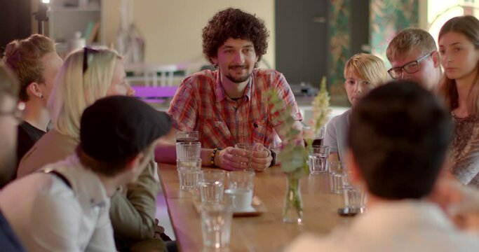 Young man is engaged in conversation at cafe table, group meeting. Expressing his needs and opinions. He employs nonviolent communication techniques, fostering a respectful and empathetic dialogue.