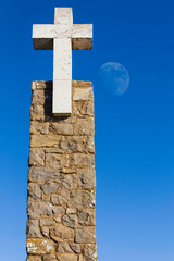 Large stone cross against the blue sky with moon,  Cape Da Roca, Cabo da Roca, Portugal