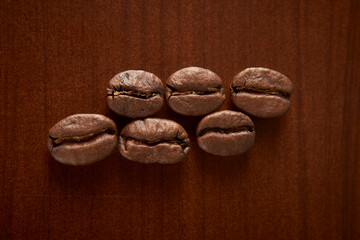 Aromatic Elegance: A close-up masterpiece capturing the intricate details of coffee beans on a rich wooden texture. The interplay of texture and aroma unfolds against a warm backdrop