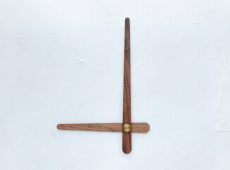 Wooden clock hands on a white wall texture rough background. The concept of running time, time for...