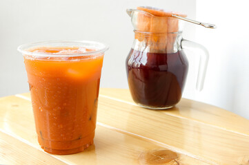 Thai Milk Tea or Milk ice tea, A glass of ice milk tea on wooden table. The orange of Thai tea (called Cha Yen in Thailand)